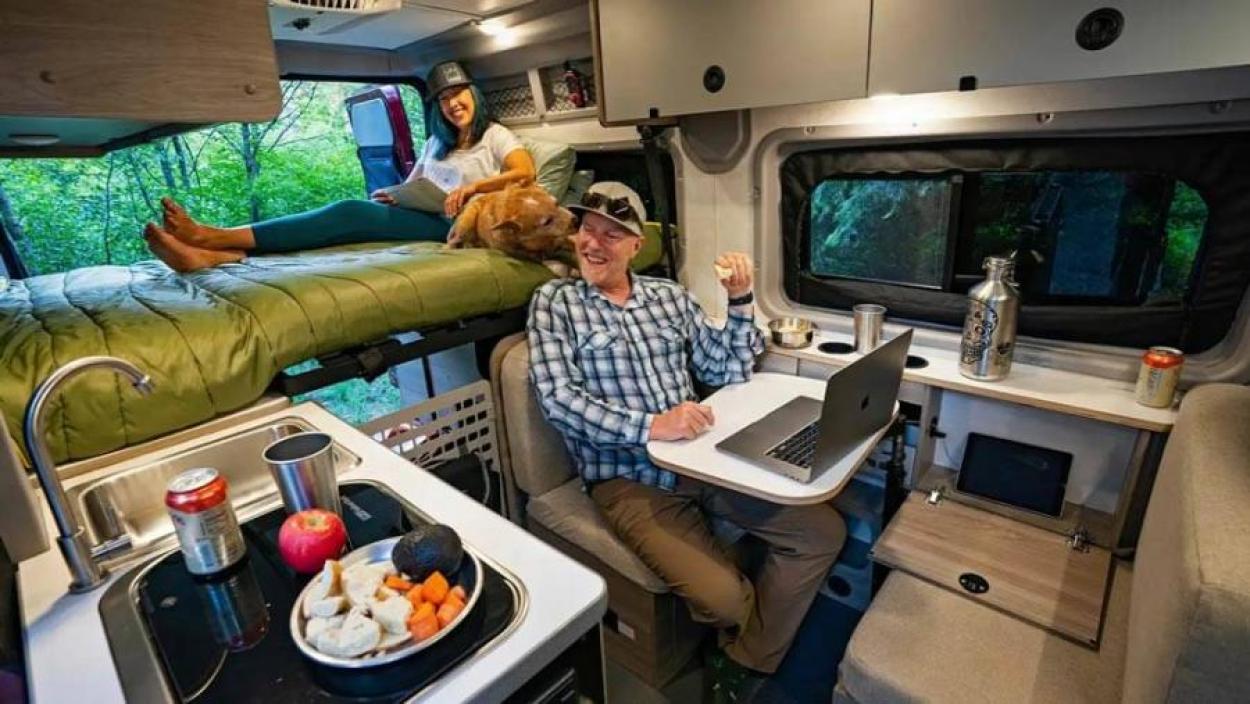 Couple hanging out inside a Winnebago Solis campervan