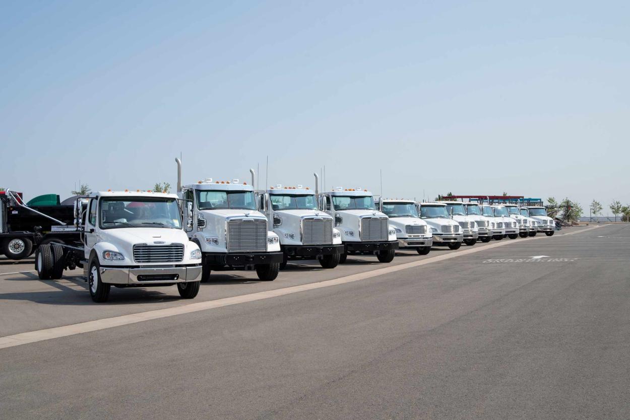 Line of commercial trucks parked under a blue sky