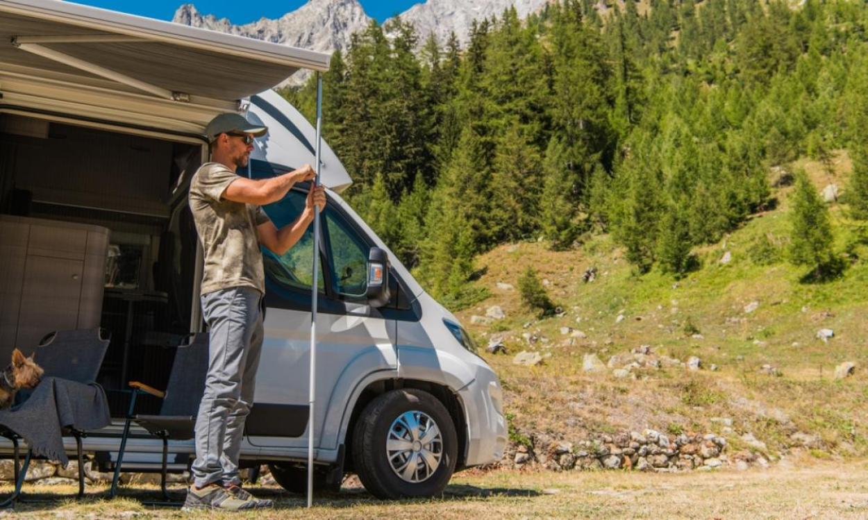 Man extends pole outside a parked RV