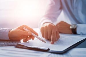 Two people&#039;s hands as they go over a contract