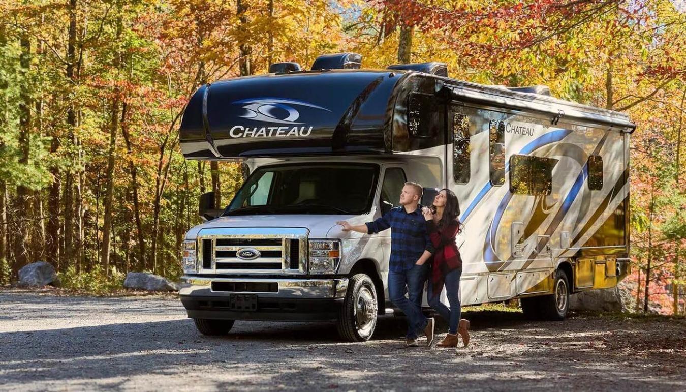 Thor RV parked outside with autumn foilage behind it