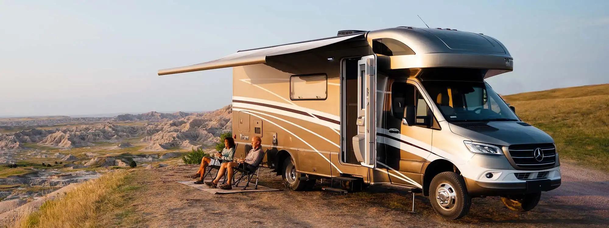 A couple sitting together under the awning of a Winnebago RV