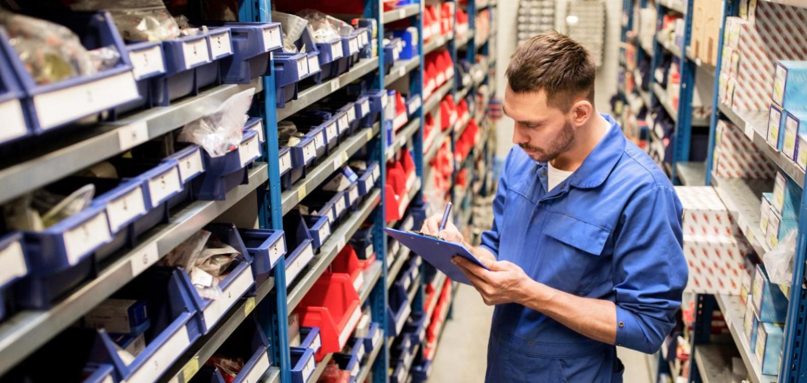 Man reviewing clipboard in an auto parts warehouse